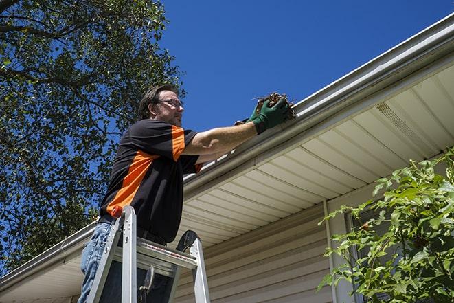 a person repairing a gutter on a residential roof in Aurora